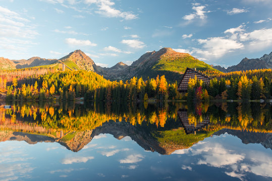 Picturesque autumn view of lake Strbske pleso in High Tatras National Park, Slovakia. Clear water with reflections of orange larch and high mountains on background. Landscape photography