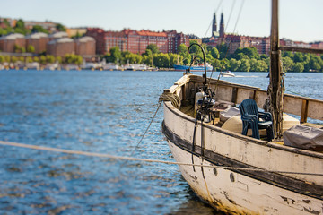 bow and deck of old pleasure boat moored to a embankment with panorama of stockholm city on a background