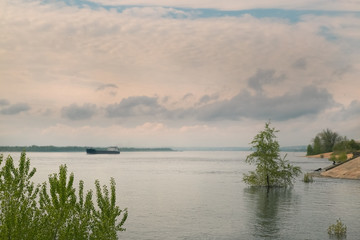 River landscape with water trees and barge. Dramatic sky clouds as background.