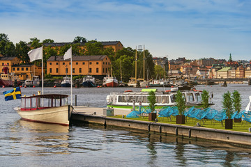 Fototapeta na wymiar pleasure boats moored at a pier with city cafe terrace on it in Stockholm city center