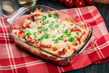 Traditional mexican enchiladas with chicken meat, spicy tomato sauce and cheese in heat resistant dish