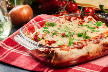 Traditional mexican enchiladas with chicken meat, spicy tomato sauce and cheese in heat resistant dish