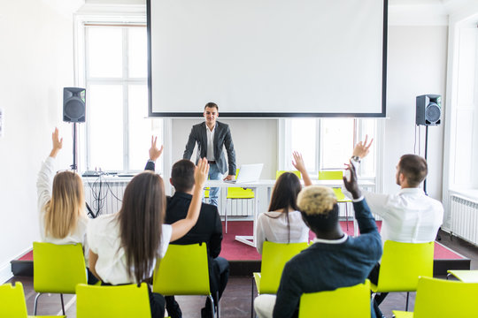 Group of business people raise hands up to agree with speaker in the meeting room seminar. Ask presenter.