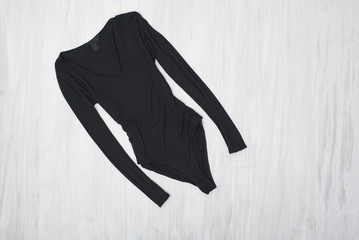 Black bodysuits with sleeves on a wooden background. Fashionable concept