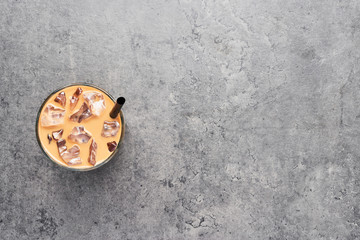 Chocolate, vanilla, caramel or cinnamon iced coffee in tall glass with black straw on grey concrete background. Top view with copy space for text.