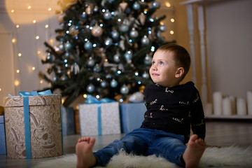 New year, Children's holiday. A little boy in a beautiful photo studio. Gifts under the Christmas tree.