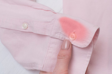 Sleeve of a pink shirt with a stain in female hand.