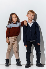 The portrait of cute little kids boy and girl in stylish jeans clothes looking at camera against...