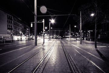 Nächtliche Straße im Stadtzentrum mit Schienen
