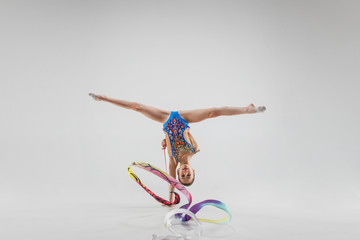 The portrait of beautiful young brunette woman gymnast training calilisthenics exercise with blue...