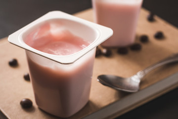 Delicious pink yogurts with a spoon on a table