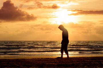 Fototapeta na wymiar Man walks and thinks at sunset on the beach