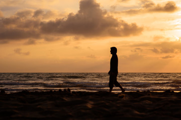 Fototapeta na wymiar Man walks and thinks at sunset on the beach