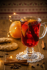 Traditional Christmas hot drink - mulled red wine - with spices, cookies and fruits on a wooden rustic table.