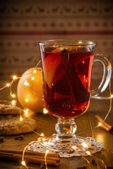 Traditional Christmas hot drink - mulled red wine - with spices, cookies and fruits on a wooden rustic table.