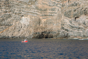 Mała, czerwona łódka na tle wielkiej skały © Agnieszka