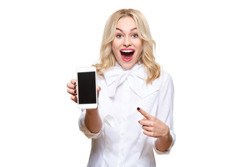 Gorgeous excited woman pointing to blank screen mobile phone over white background, celebrating...