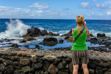 Kobieta fotografująca fale rozbijające się o kamienie © Agnieszka
