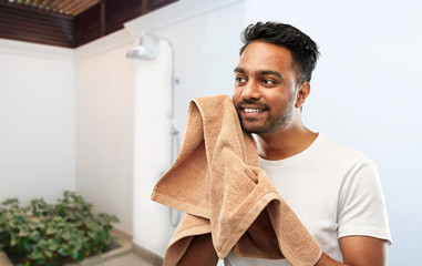 grooming, hygiene and people concept - smiling indian man with bath towel drying his face over...