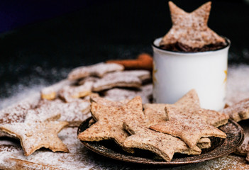 Star shaped christmas cookies decorated sugar and cocoa powder, a cup of hot chocolate.
