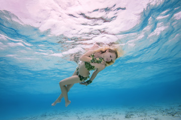 Golden-haired nymph swim underwater surface in blue water, Indian Ocean, Maldives