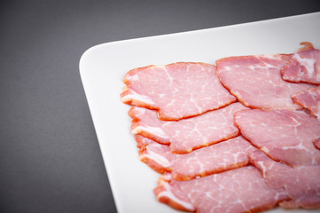 meat sliced in a plate on a dark background close-up