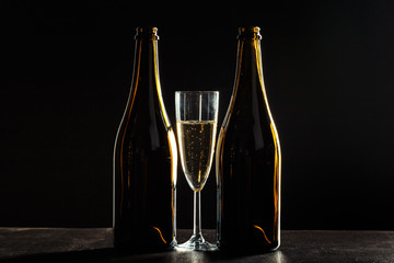 bottle of champagne and glasses over dark background