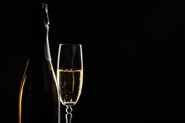 bottle of champagne and glasses over dark background