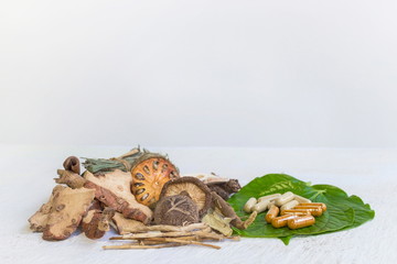 Dried herbs and Herbal medicine pill on a white wooden table and white background, image with copy space for text or image.