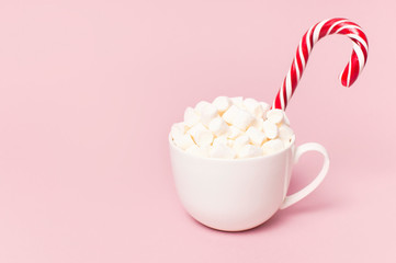 Christmas New Year drink, white mug with marshmallows and Candy Cane on pink background Flat Lay copy space. Winter traditional drink food. Festive decor, celebration Xmas holiday 2019