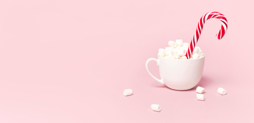 Christmas New Year drink, white mug with marshmallows and Candy Cane on pink background Flat Lay copy space. Winter traditional drink food. Festive decor, celebration Xmas holiday 2019