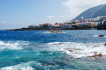 Fototapeta premium View of the town of Garachico from the ocean. Natural rock pools, old historical buildings and Santa Ana church on the background. Tenerife North, Canary Islands, Spain. 