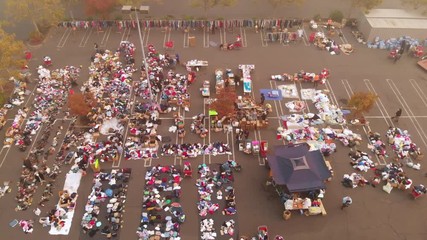 Aerial shot through smoke from the Camp Fire in Paradise California over parking lot distribution center for victims.
