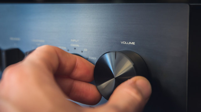 Hand turning a knob with output volume text written on it, with the consequence of a cost per unit reduction. Composite image between a photography and a 3D background.