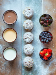 muffins with powdered sugar and almond, blackberry, strawberry, blueberry, yogurt, drink, chocolate milk on the wooden table