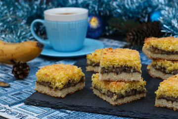 Banana cake with coconut flakes - festive dessert for Christmas, New Year, Close-up. In the background a cup of coffee. 