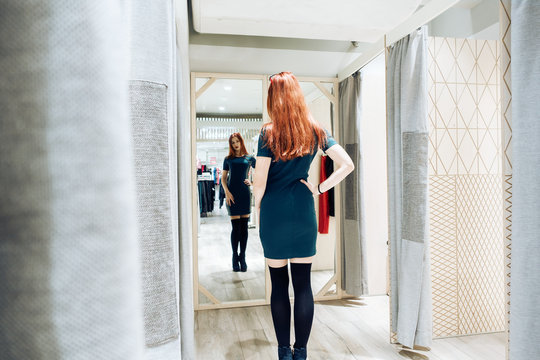 Young Beautiful Girl Trying On New Green Dress In The Fitting Room In Boutique.