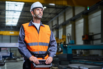Portrait of man in factory operating machinery with remote console