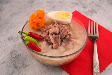 Nutritious jelly with meat. Half boiled egg. Sliced raw carrots. Hot pepper. Light background.