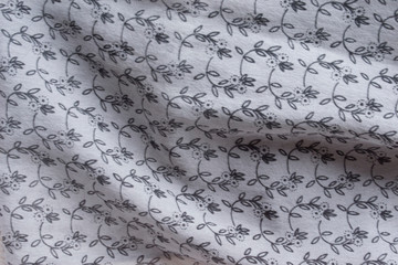 Background. An abstract pattern on fabric. Gray, silver, gloss, rhinestones. Folds, drapery, silk. Flower print.