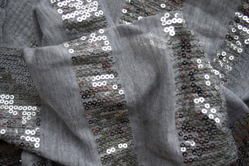 Background. An abstract pattern on fabric. Gray, silver, gloss, rhinestones. Folds, drapery, silk.
