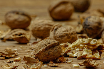 Walnuts and cracked walnuts on wooden table. Close-up, healthy food with rustic background.