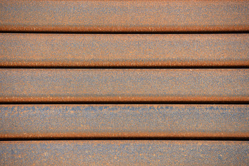 Rusty rectangular metal pipe in the packs are stored in the metal products warehouse. Steel materials, construction supplies.