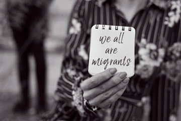 woman and note with the text we all are migrants
