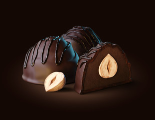 3d render of dark chocolate candies with dark truffle filling and whole hazelnut inside