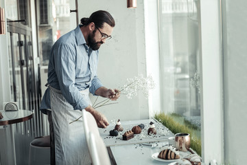 Nice professional male baker decorating the dish