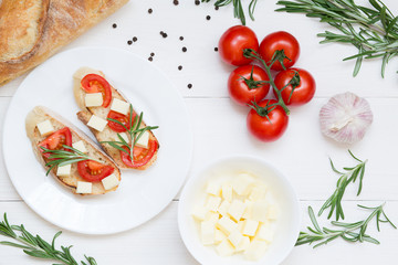 Bruschetta toasts with mozzarella, cherry tomatoes and fresh garden rosemary. Top view with space for your text