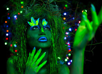 Mystic green dryad in UV fluor black light with Glowing trees on background