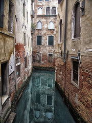 a quiet narrow canal in venice surrounded by picturesque ancient buildings reflected in the water