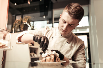 Smart professional confectioner looking at the croissant